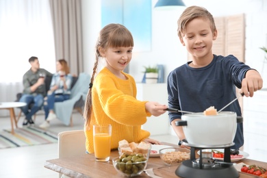 Photo of Happy kids enjoying fondue dinner at home