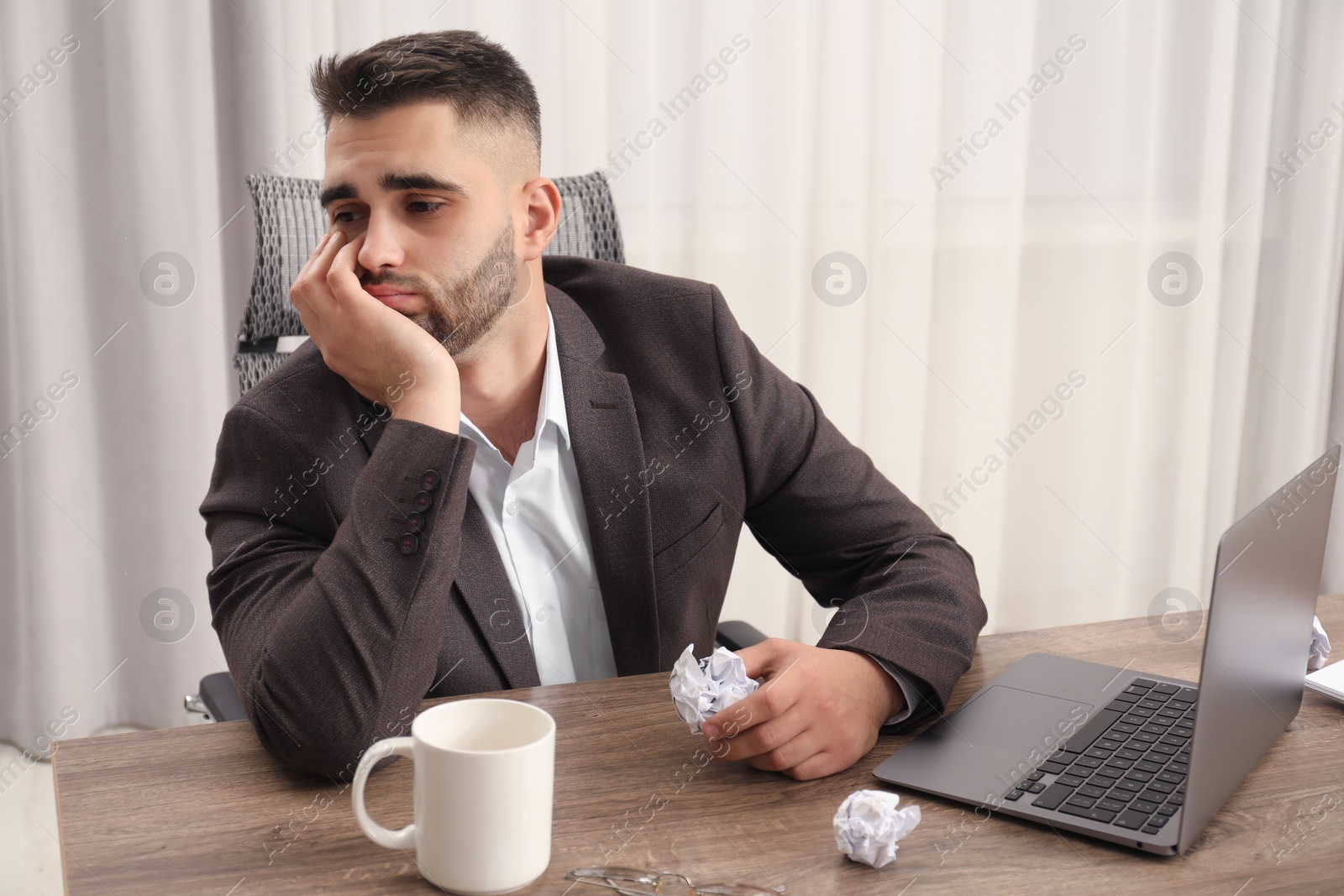 Photo of Sad businessman sitting at table in office