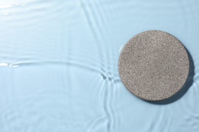 Photo of Presentation of product. Stone podium in water on light blue background, top view. Space for text