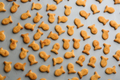 Photo of Delicious goldfish crackers on grey table, flat lay