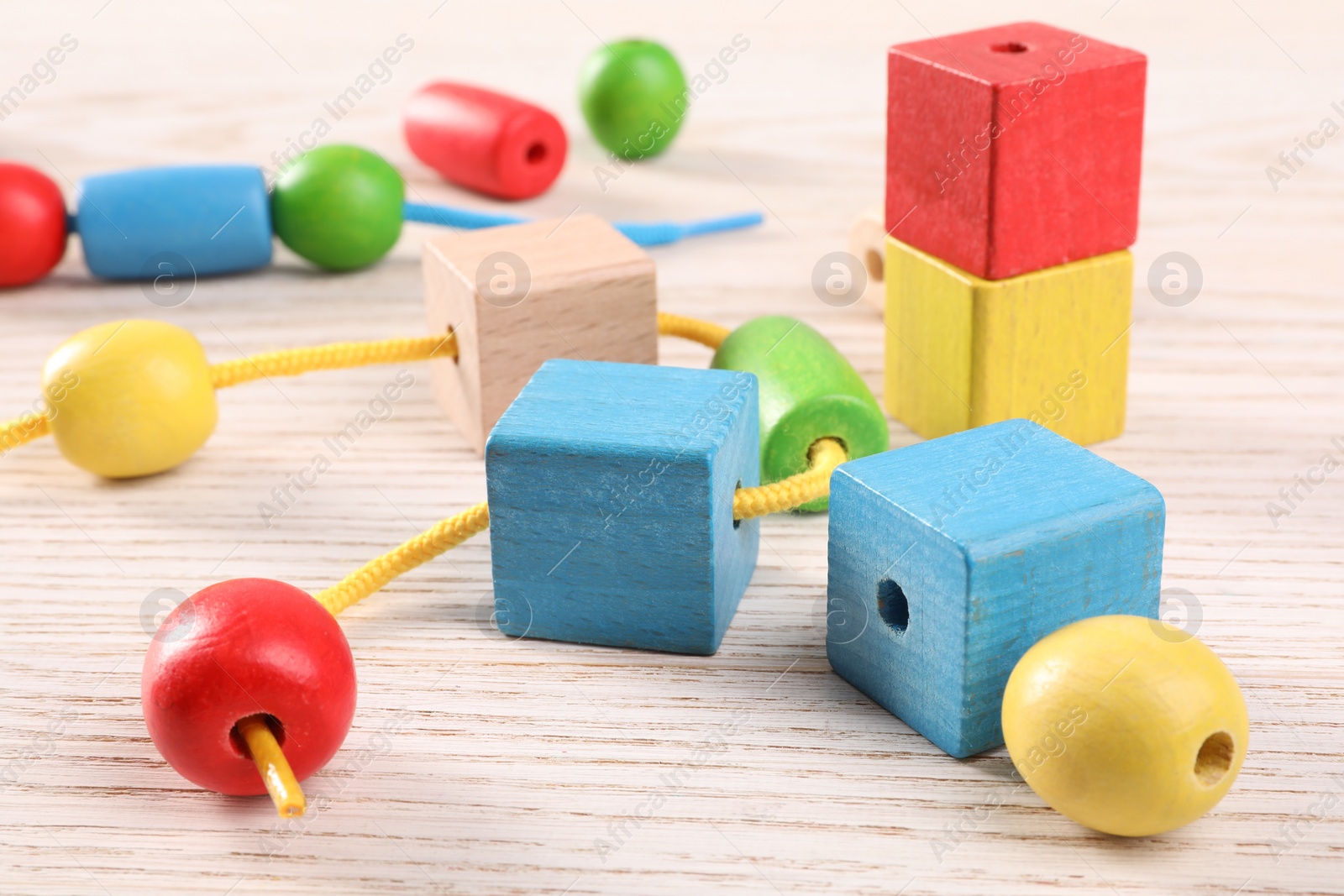 Photo of Wooden pieces and string for threading activity on light table, closeup. Motor skills development