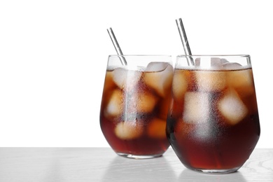 Tasty cola with ice cubes on table against white background