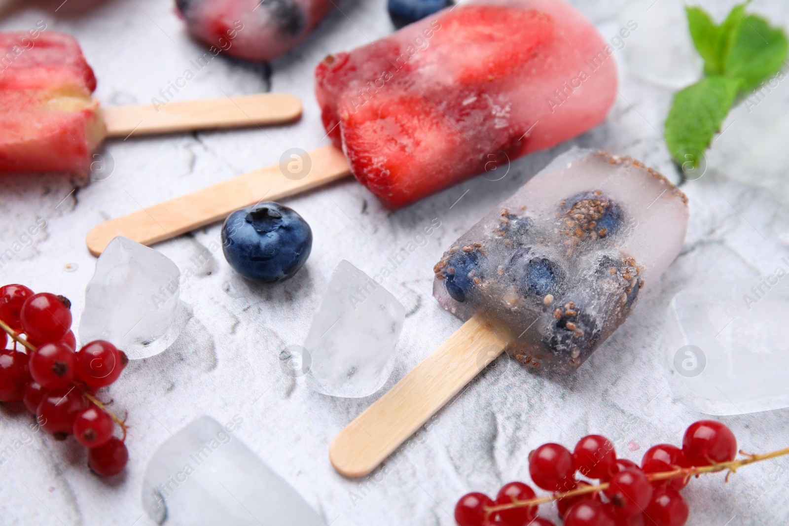 Photo of Tasty fruit and berry ice pops on light table, closeup