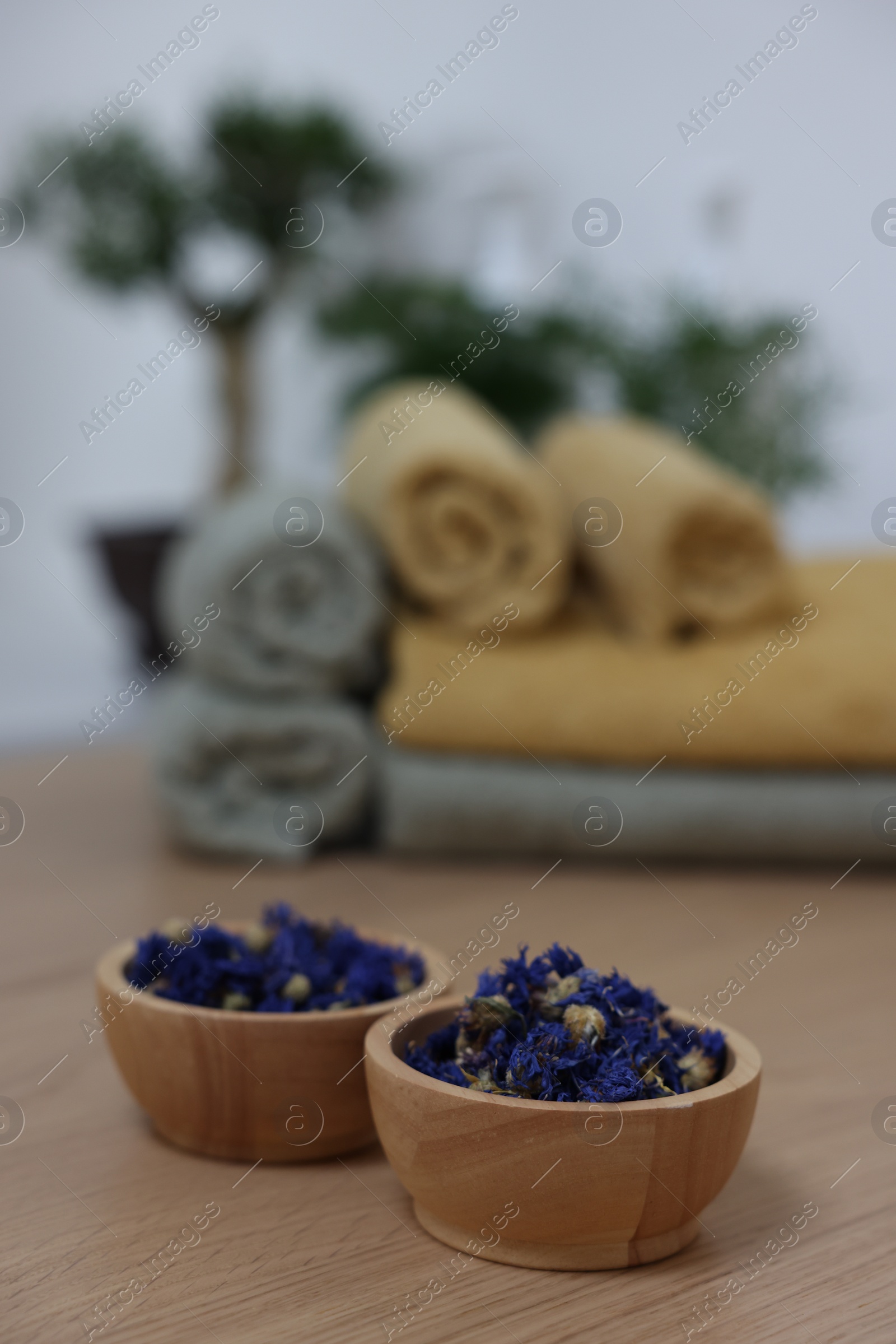 Photo of Bowls with dry flowers on light wooden table, space for text. Spa