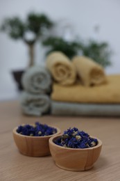 Bowls with dry flowers on light wooden table, space for text. Spa