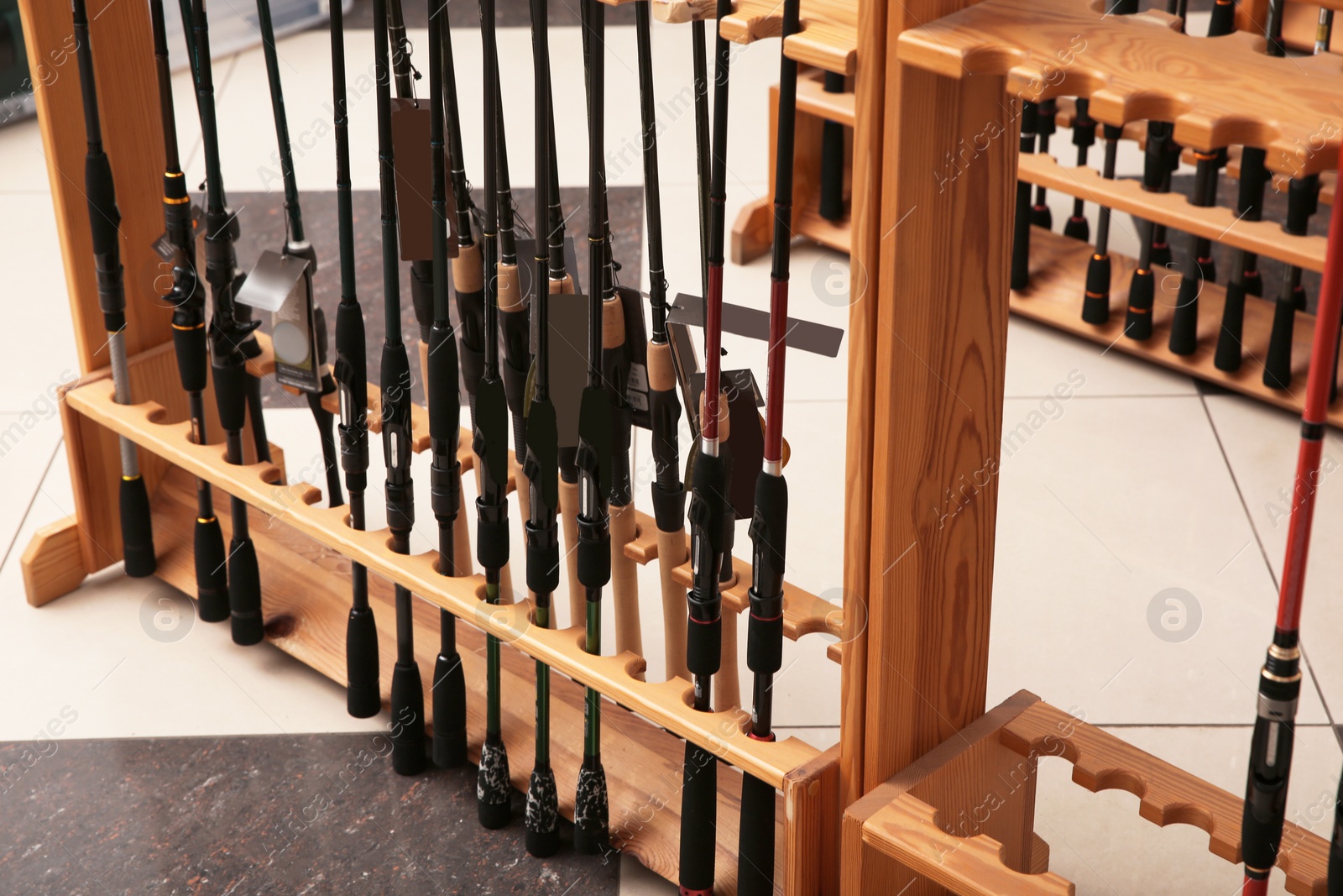 Photo of Stand with different fishing rods in sports shop, closeup