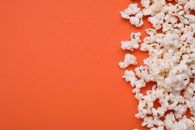 Tasty popcorn scattered on orange background, flat lay. Space for text