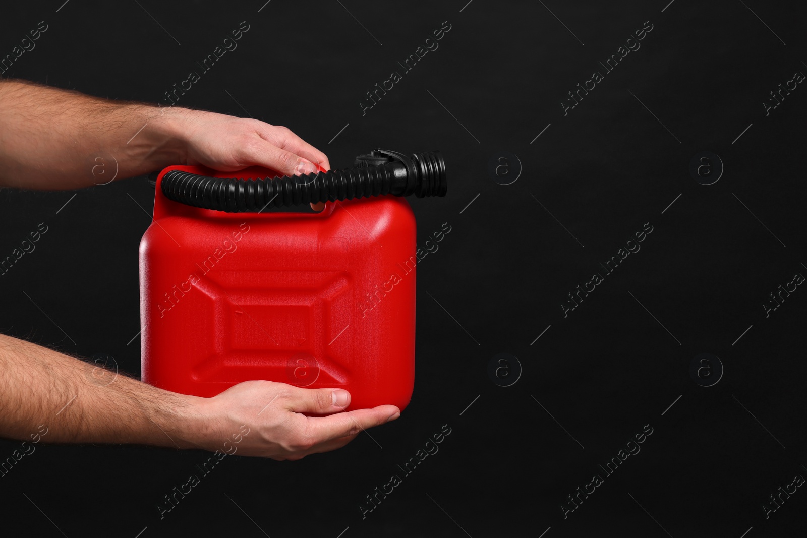 Photo of Man holding red canister on black background, closeup. Space for text