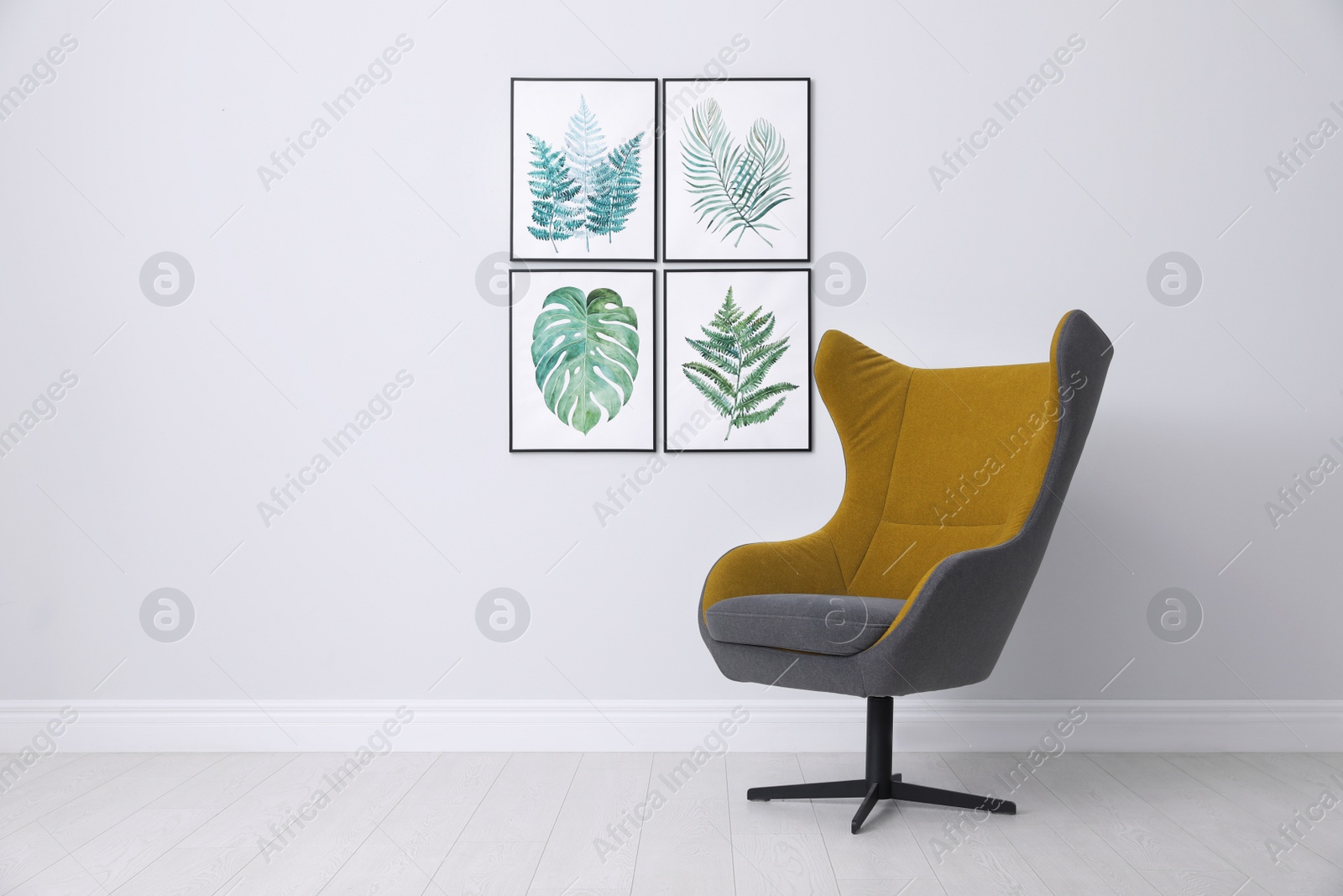 Photo of Stylish comfortable armchair and paintings of tropical leaves. Interior design