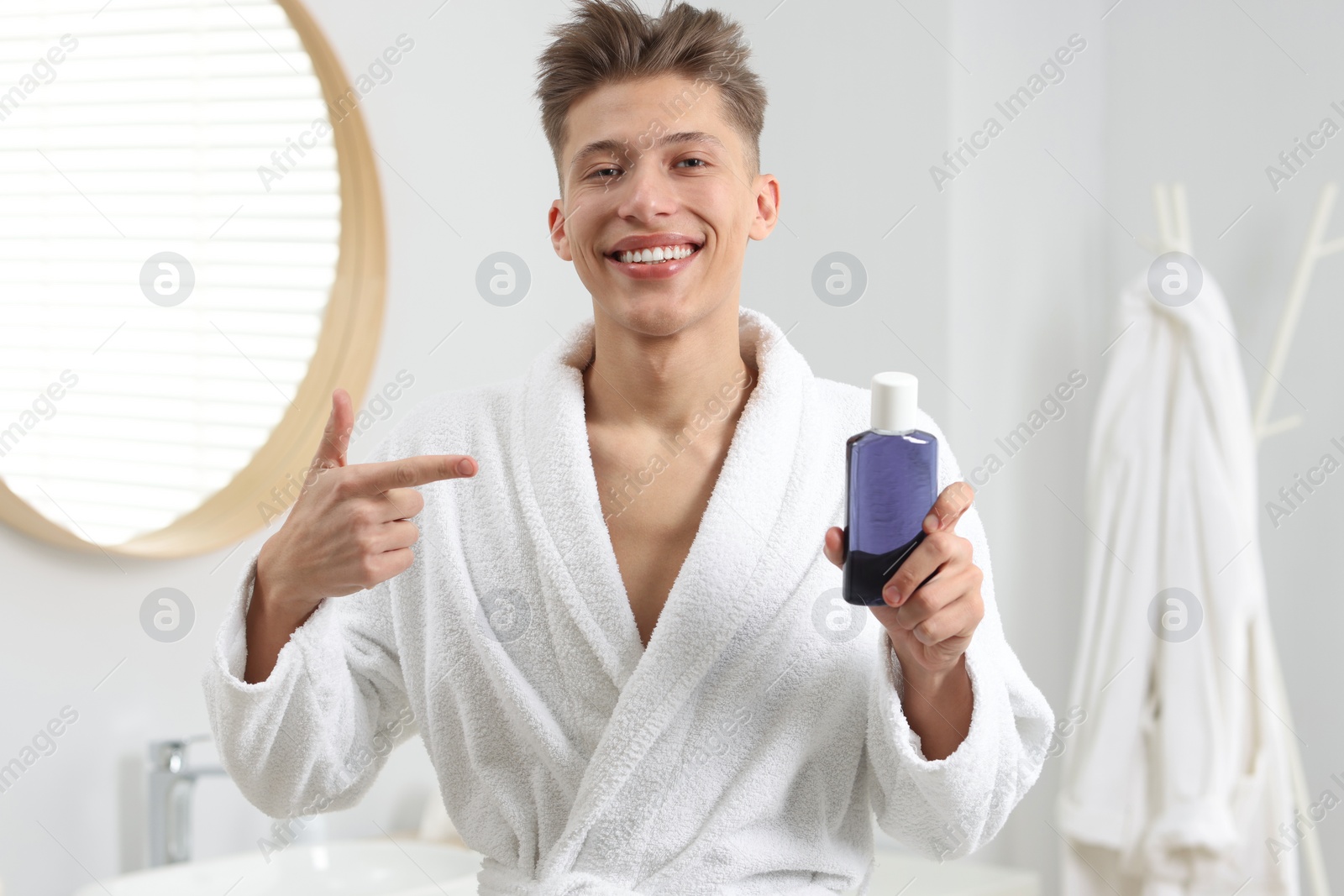 Photo of Young man pointing at mouthwash in bathroom