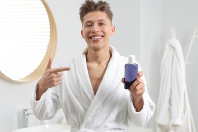 Photo of Young man pointing at mouthwash in bathroom