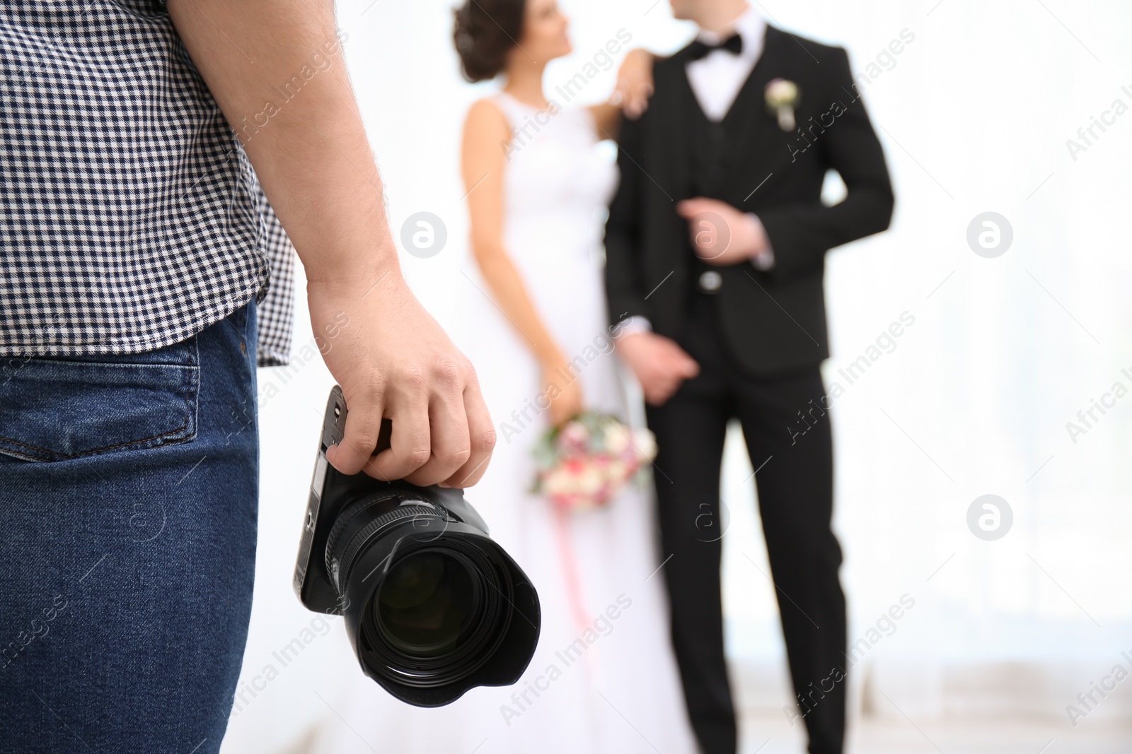 Photo of Professional photographer with camera and wedding couple in studio