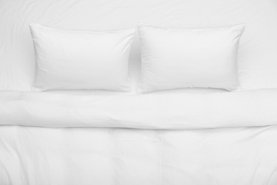 Photo of Soft white pillows and blanket on bed, top view