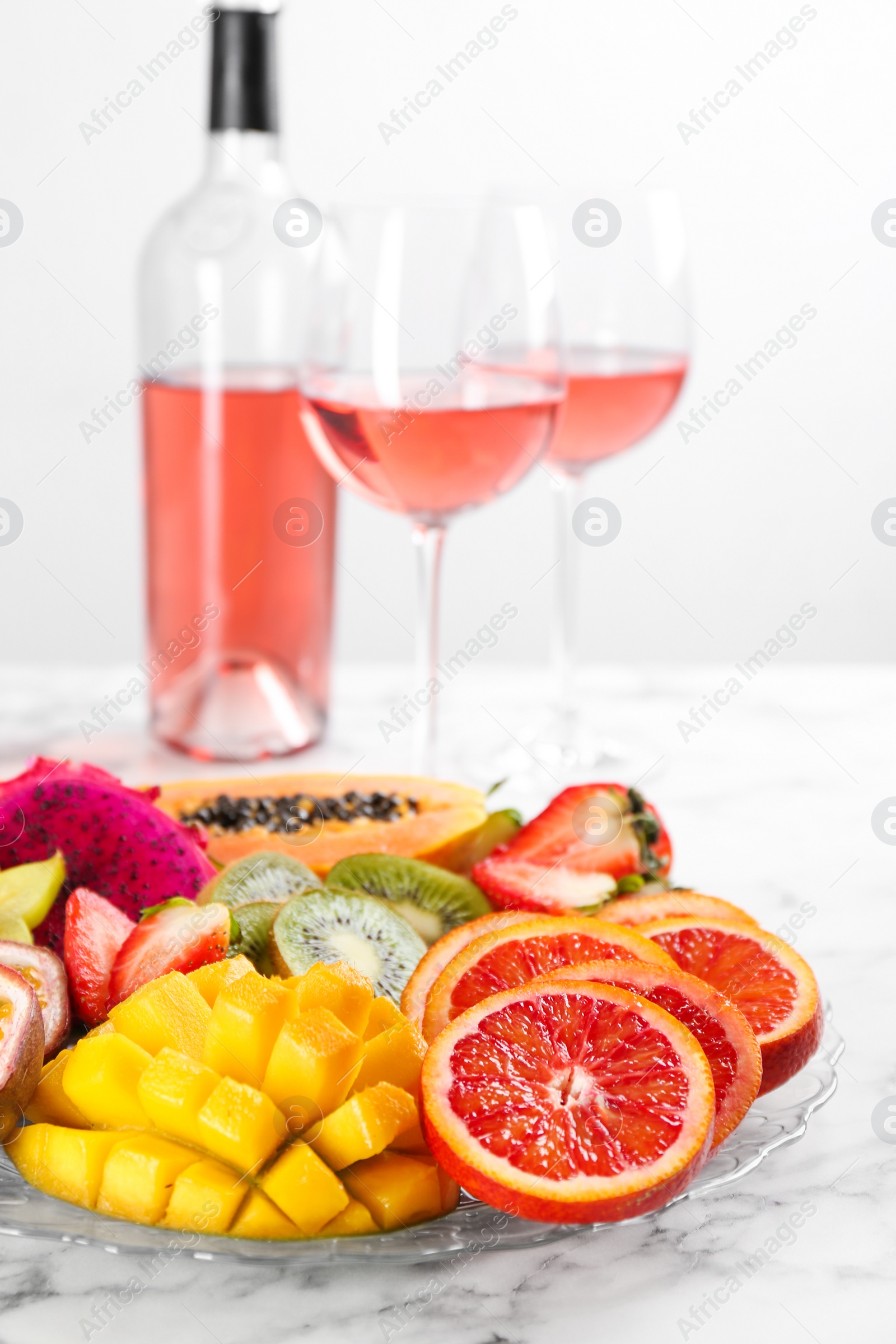 Photo of Delicious exotic fruits and wine on white table