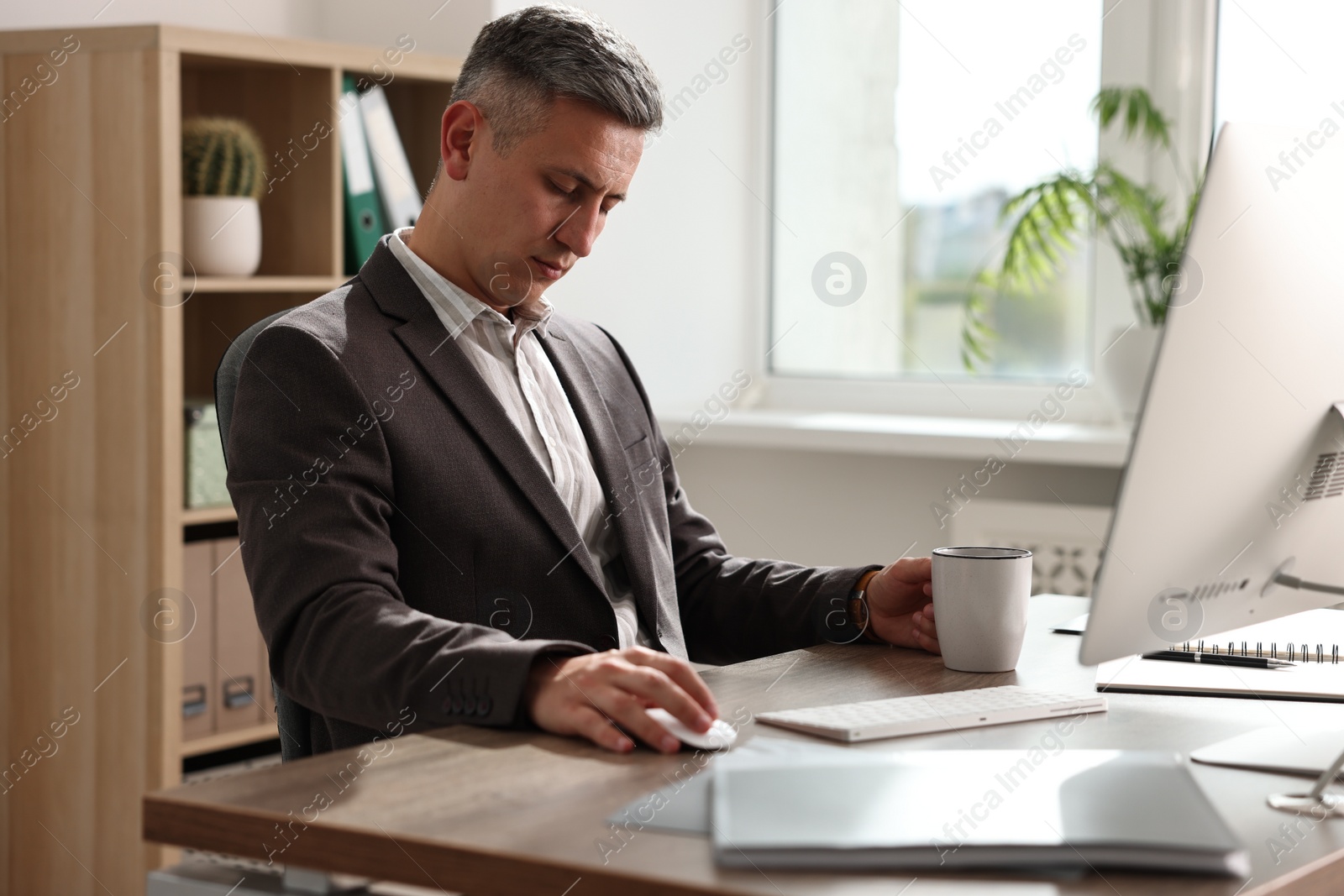 Photo of Man with cup of drink snoozing at table in office