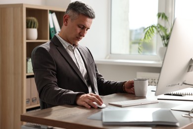 Man with cup of drink snoozing at table in office