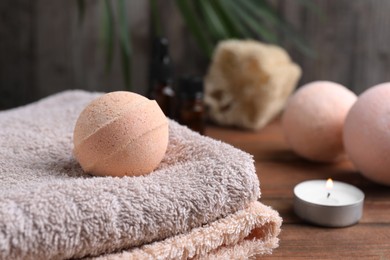 Beautiful aromatic bath bomb and towel on wooden table, closeup. Space for text
