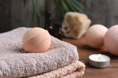 Photo of Beautiful aromatic bath bomb and towel on wooden table, closeup. Space for text