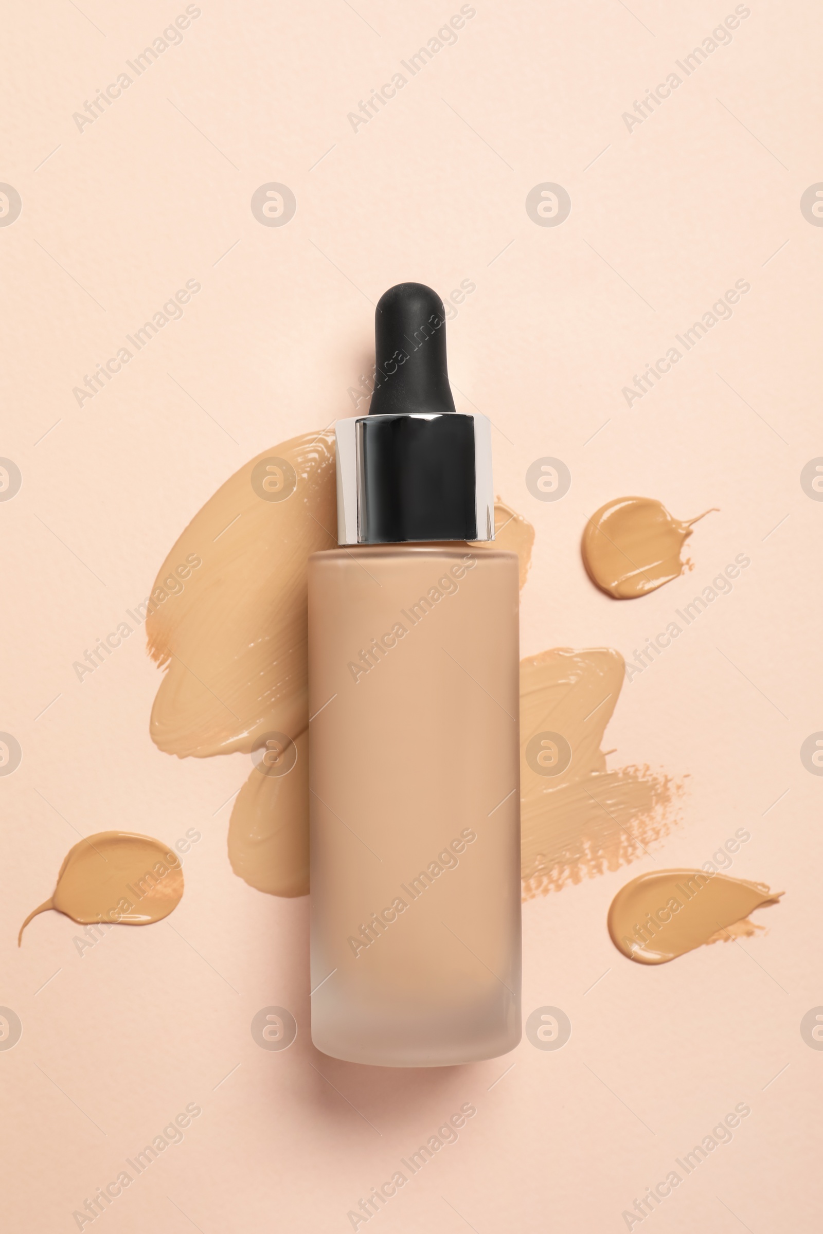 Photo of Liquid foundation and swatches on beige background, top view