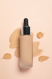 Liquid foundation and swatches on beige background, top view