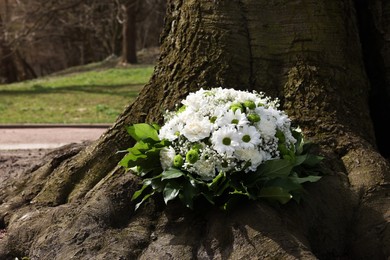Funeral wreath of flowers near tree outdoors