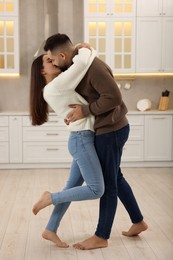 Photo of Affectionate young couple kissing and hugging in kitchen