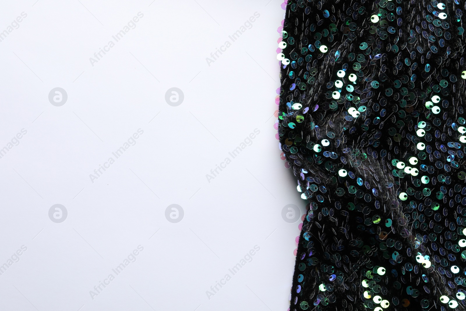 Photo of Dark shiny sequin fabric on white background, top view. Space for text