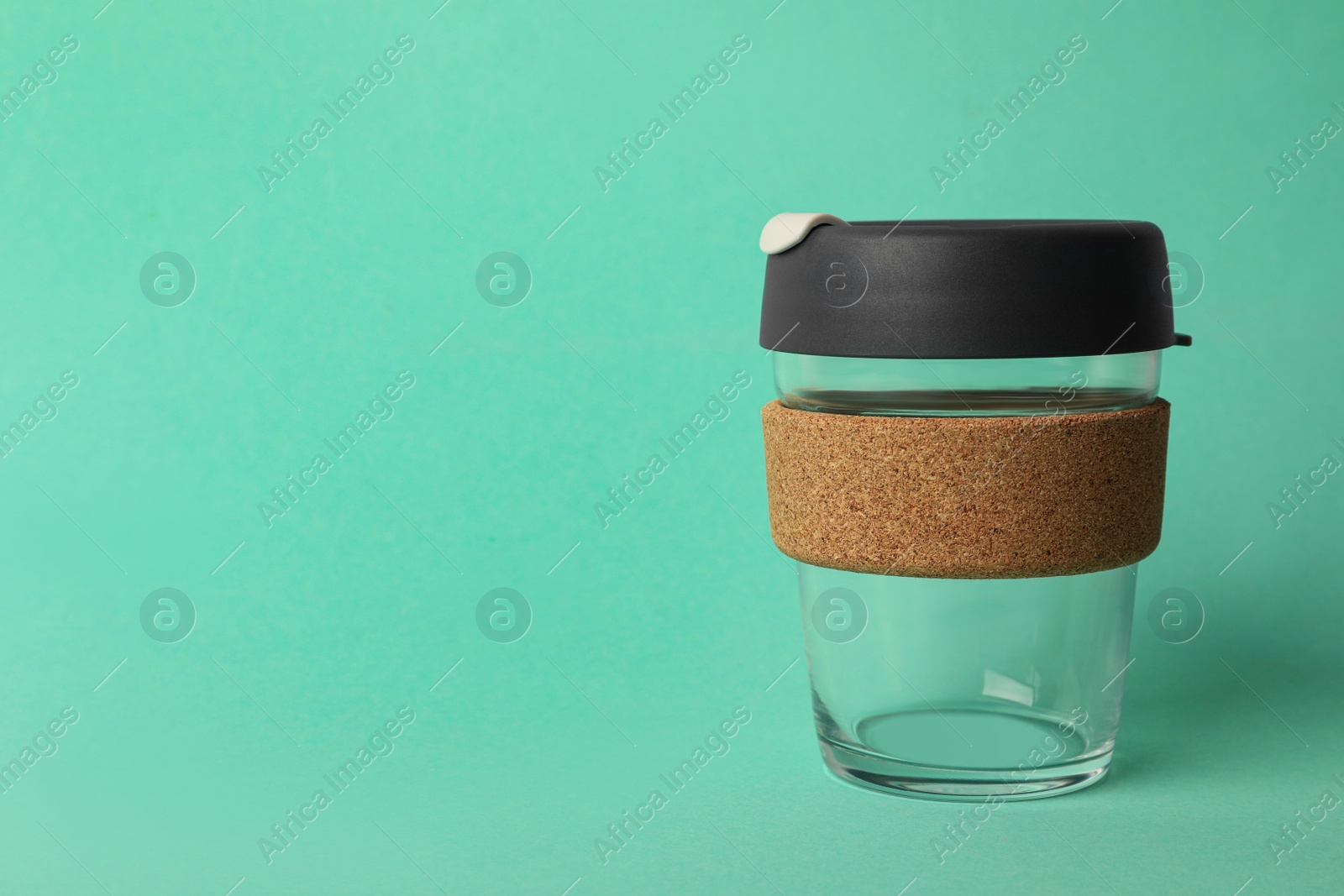 Photo of Glass cup with sleeve on turquoise background, space for text. Conscious consumption