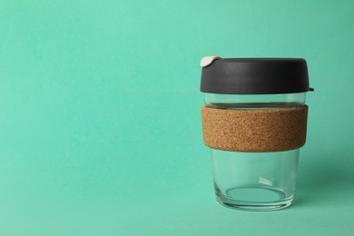 Photo of Glass cup with sleeve on turquoise background, space for text. Conscious consumption