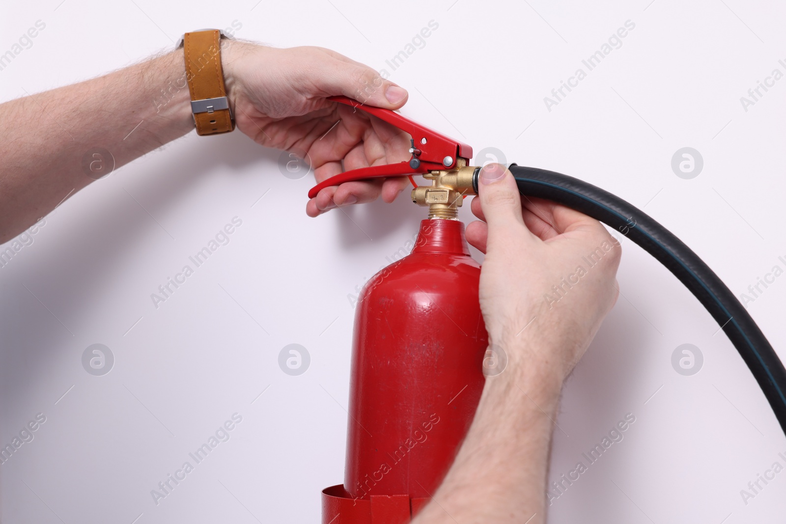 Photo of Man checking quality of fire extinguisher indoors, closeup