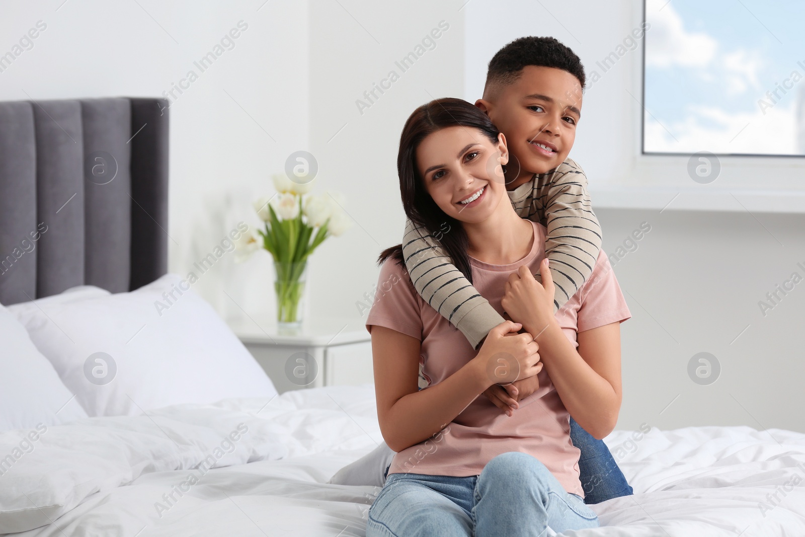 Photo of Mother with her African American son on bed at home. International family