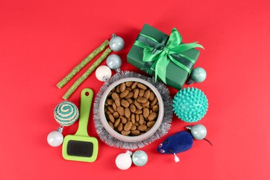 Photo of Flat lay composition with different pet goods and Christmas gift on red background. Shop assortment