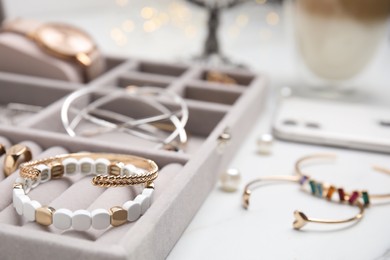 Photo of Elegant jewelry box with beautiful bijouterie on white table, closeup