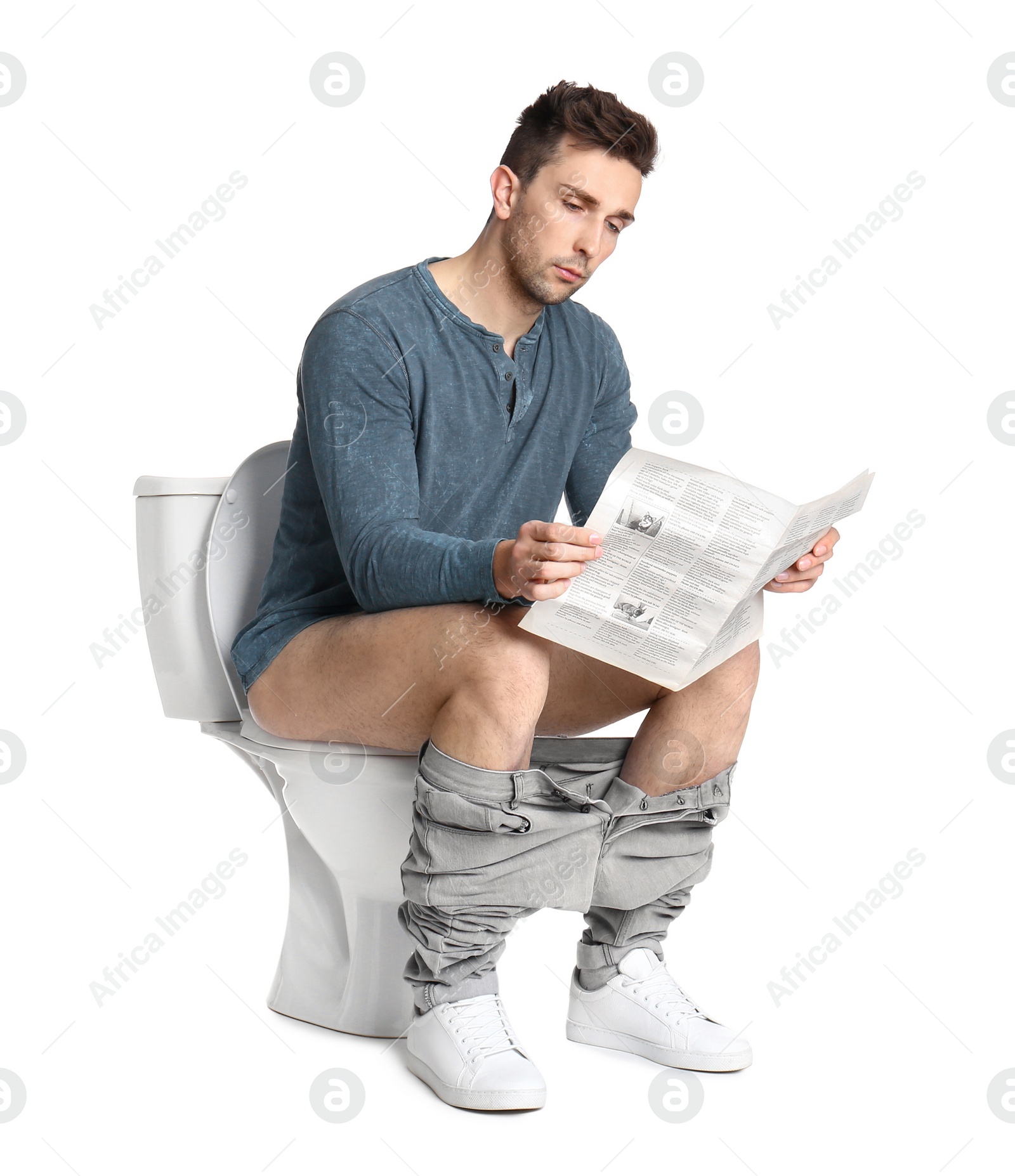 Photo of Man with newspaper sitting on toilet bowl, white background