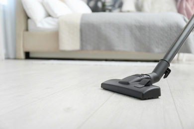 Hoovering floor with modern vacuum cleaner. Space for text