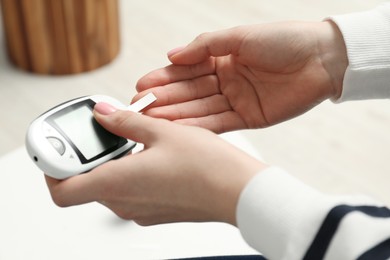 Diabetes. Woman checking blood sugar level with glucometer at home, closeup