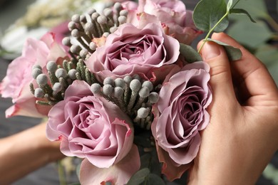 Florist creating beautiful bouquet with roses, closeup