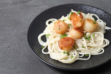 Delicious scallop pasta with green onion on grey table, closeup. Space for text