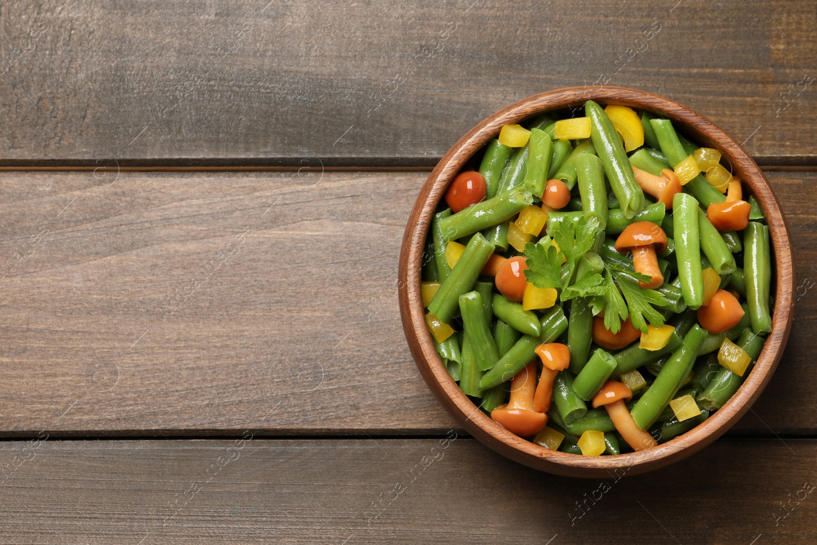 Photo of Bowl of tasty salad with green beans on wooden table, top view. Space for text