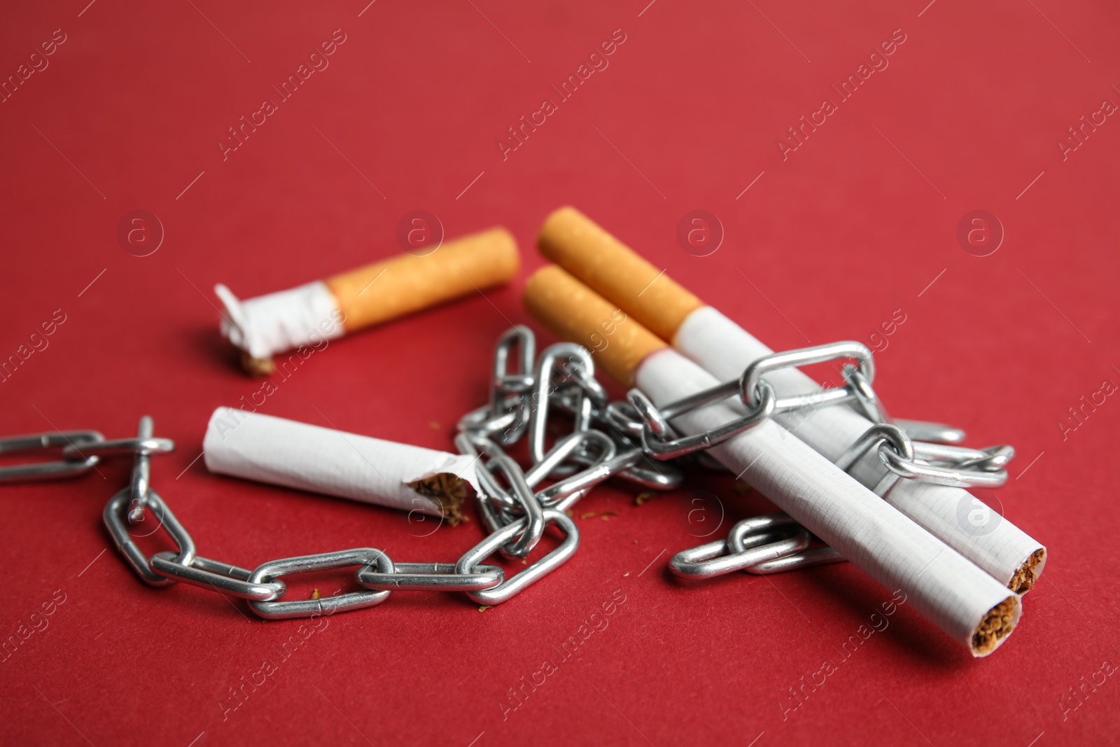 Photo of Cigarettes and chain on red background. Quitting smoking concept