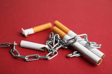 Cigarettes and chain on red background. Quitting smoking concept