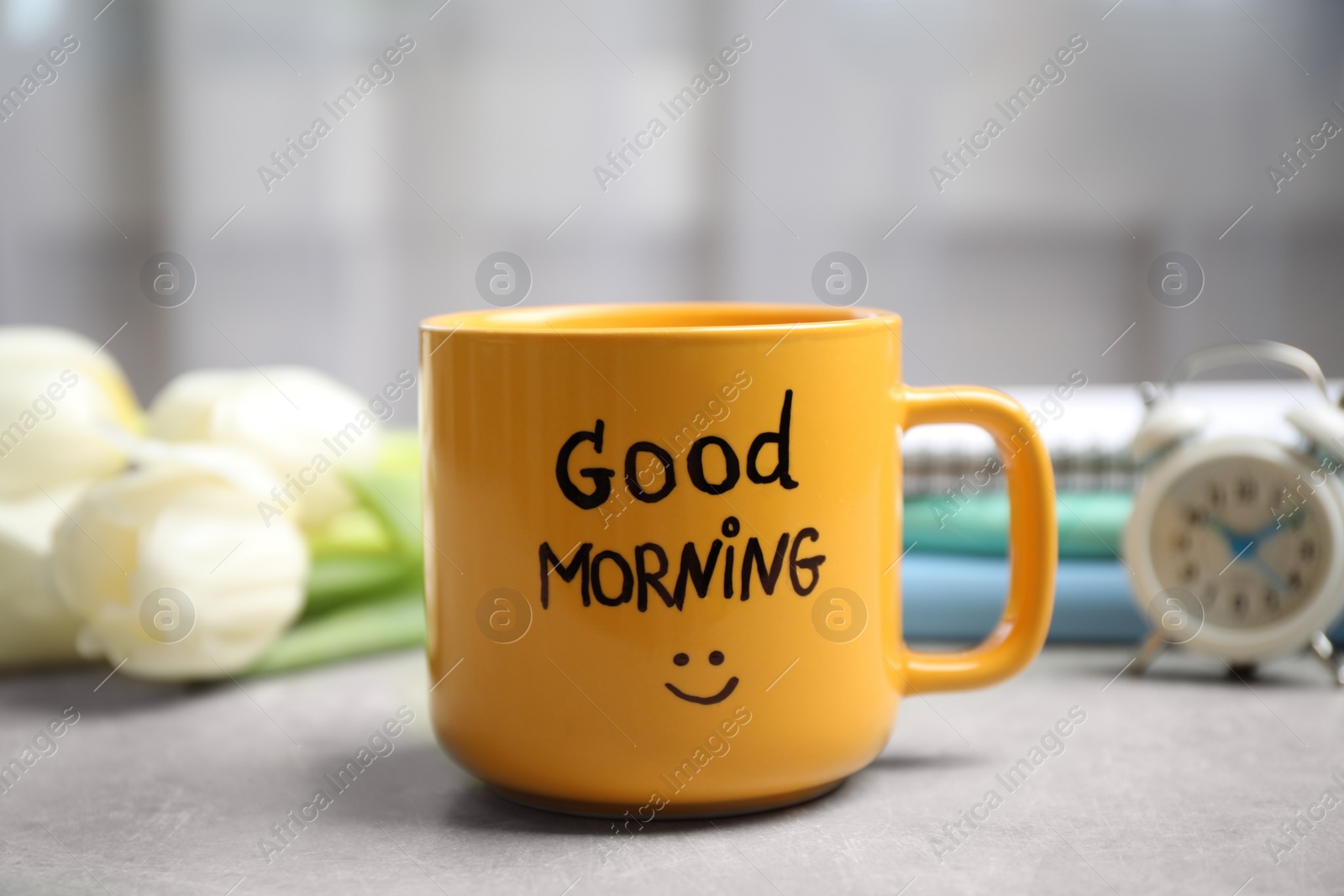 Photo of Cup of coffee with good morning wish on light grey table, closeup