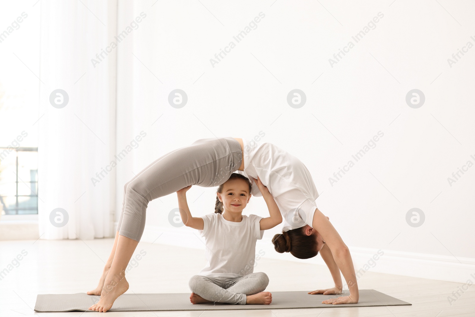 Photo of Young mother with little daughter practicing yoga at home