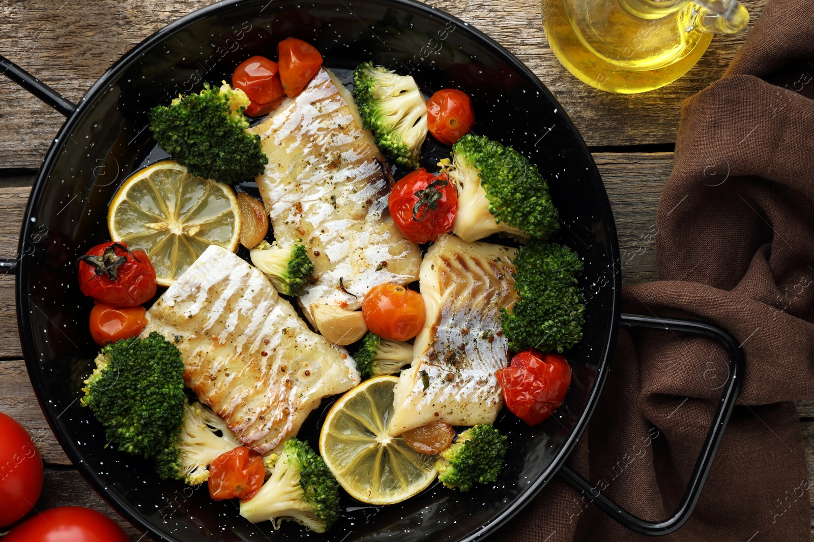 Photo of Tasty cod cooked with vegetables in frying pan on wooden table, flat lay