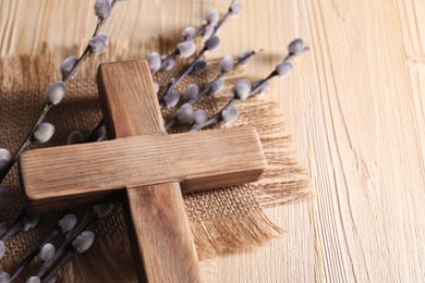 Photo of Cross and willow branches on wooden table, space for text