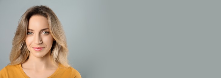 Portrait of happy young woman with beautiful blonde hair on grey background, space for text. Horizontal banner design