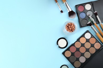 Flat lay composition with makeup brushes on light blue background, space for text