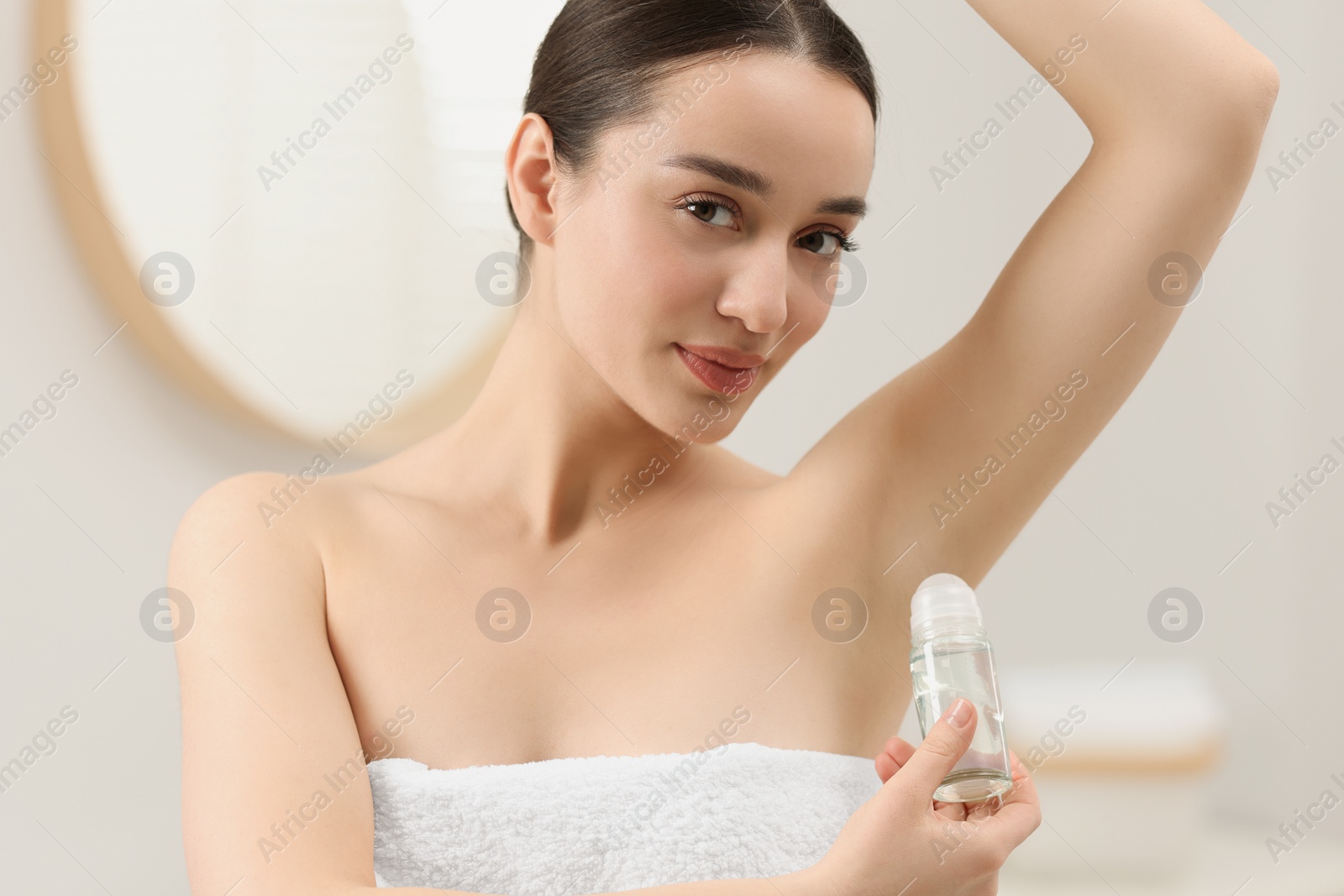 Photo of Beautiful young woman applying deodorant in bathroom