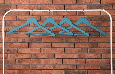 Photo of Blue clothes hangers on rack near red brick wall