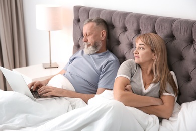 Mature couple with problem in relationship on bed at home